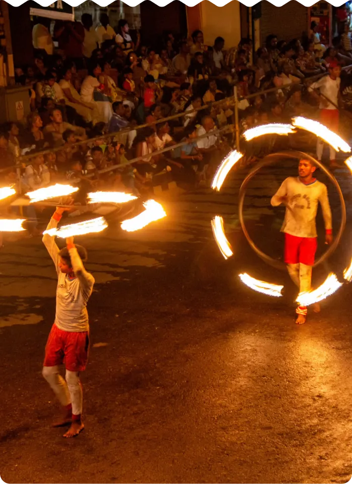 Fire dancers spinning flaming hoops in front of a festival crowd